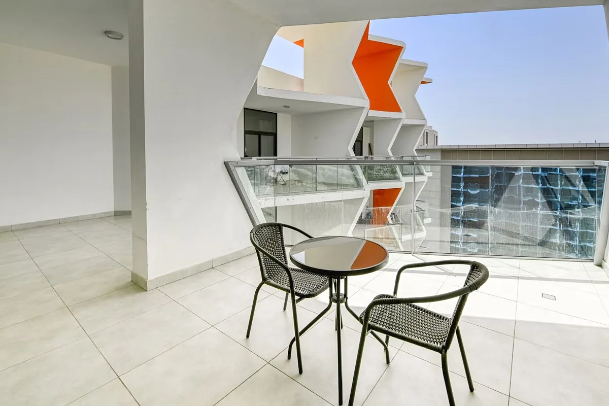 Private balcony with table and chairs, orange façade fins beyond