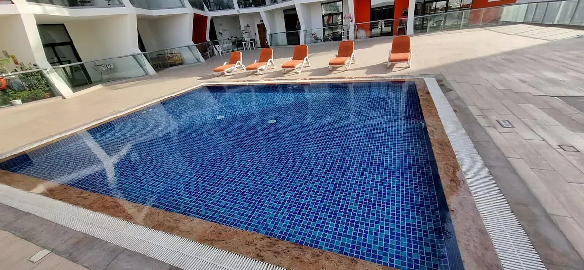 Tiled swimming pool with orange sun loungers
